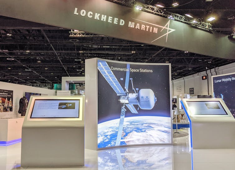 Un stand de exhibición de una convención corporativa con una fotografía gigante de una estación espacial. 