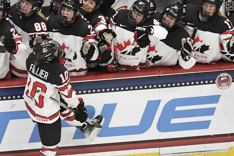 A woman wearing a team Canada jersey skates past and highfives her teammates