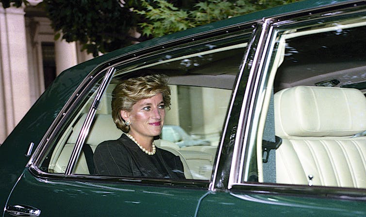 Princess Diana in the back of a green car.