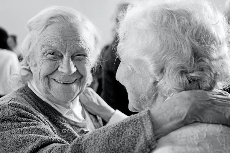Deux vieilles femmes enlacées et souriantes