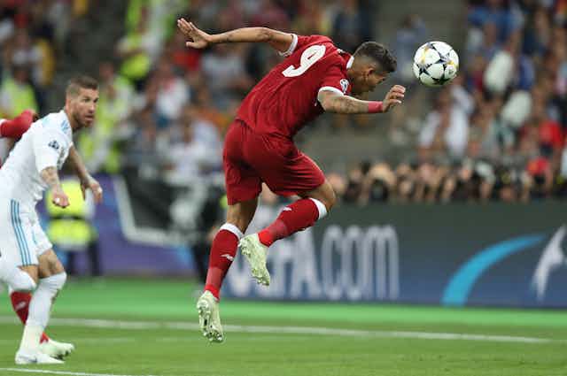 A professional footballer heads the ball.