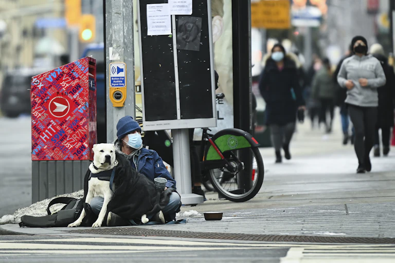 A man sits with his dog on a street corner in downtown Toronto