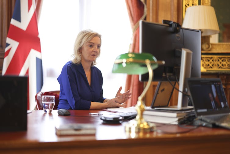 Liz Truss sitting at a desk talking to someone online.