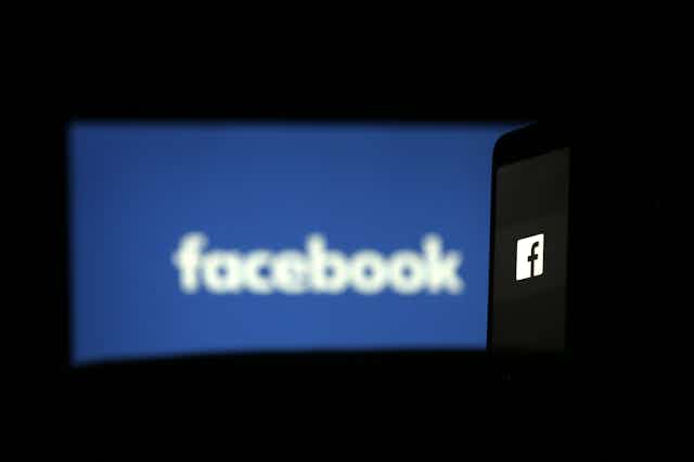 an out-of-focus image of the word facebook on a horizontal blue rectangle against a black background