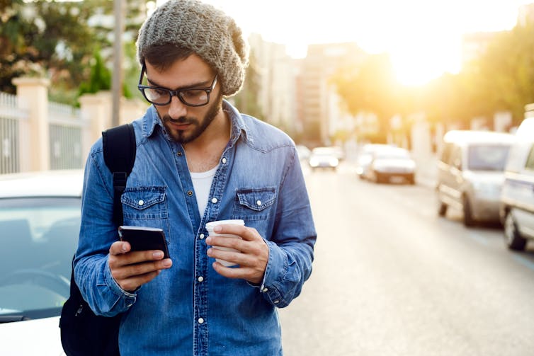 Young man on his phone with a coffee.