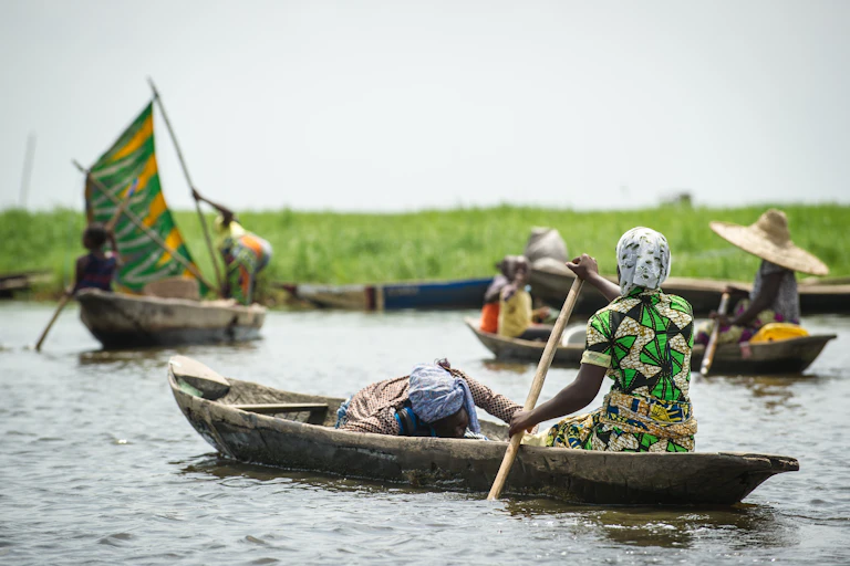 A woman rows her canoe across a stretch of water.