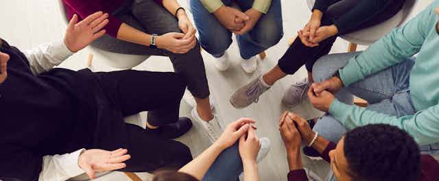An overhead shot of a group of people engaged in a group therapy session. 