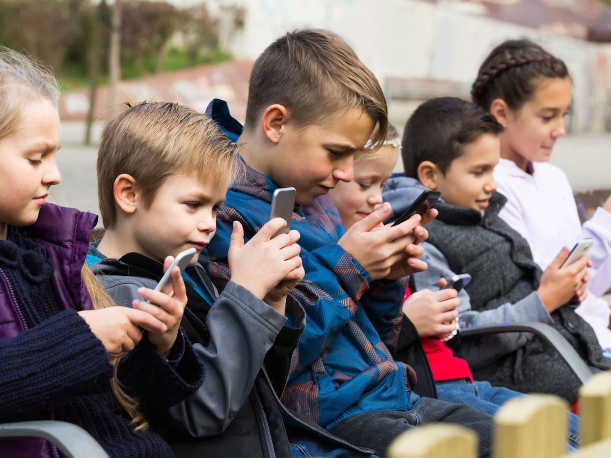 niños con teléfonos móviles enganchados todos a las pantallas