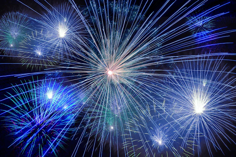 Blue and white fireworks exploding in night sky