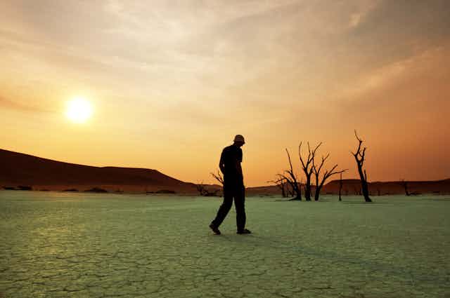 Man walks through dry lake bed