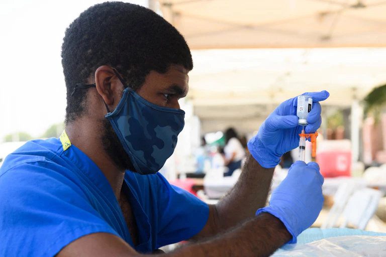 A health care worker wearing a mask and gloves prepares a dose of the Moderna Covid-19 vaccine.