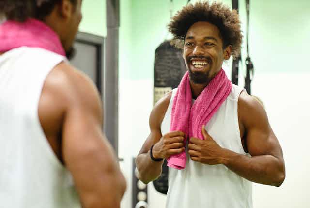 A young man looking into the mirror in a fitness class.