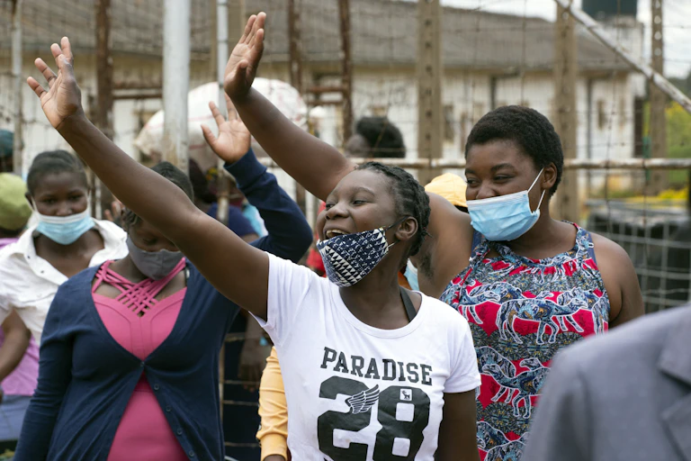 Women wearing masks smile and wave.