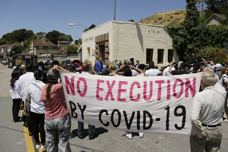 Protesters hold up a banner that says No Execution by COVID-19 outside a prison.