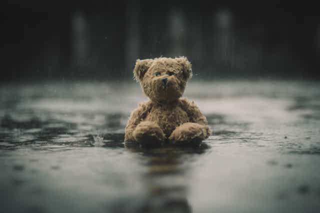 Old teddy bear sitting in the rain