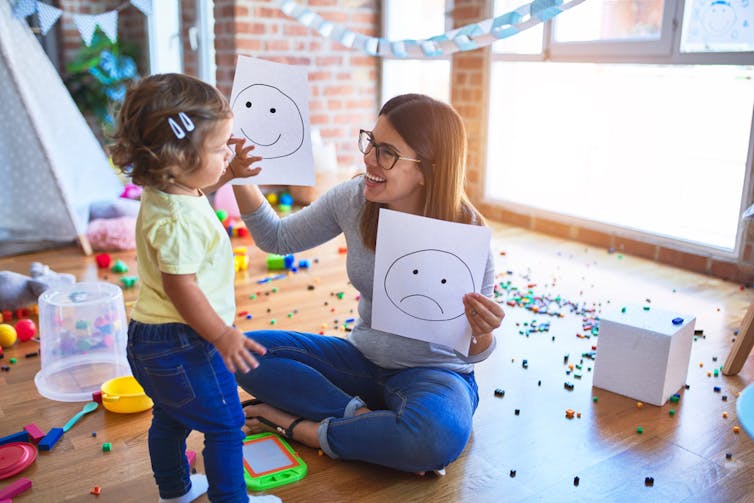 Therapist holding up emojis to toddler
