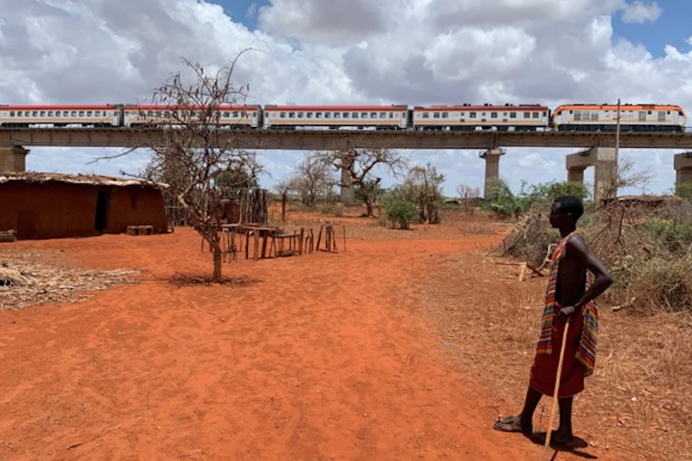 : A young man watches a passing train.