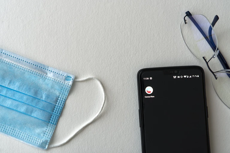 A nose mask, a mobile phone and a pair of spectacles on a table