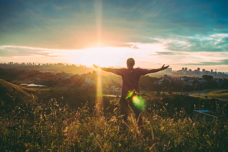 Man standing with open arms at sunrise