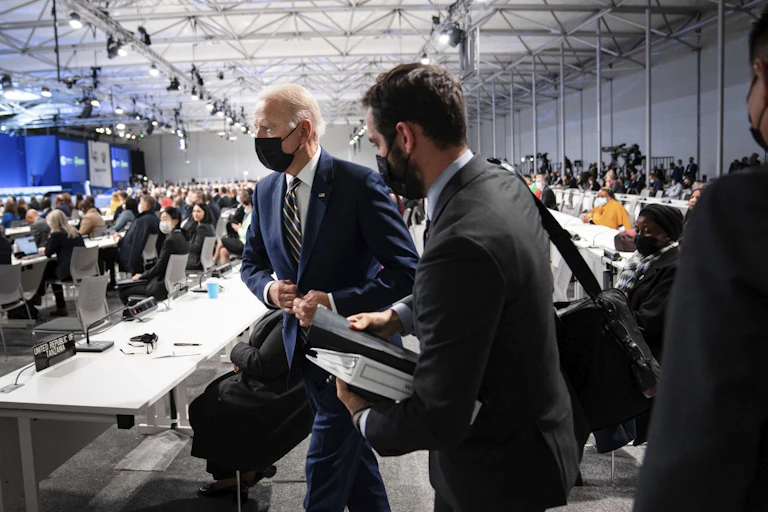 Biden walking with a room of people behind him