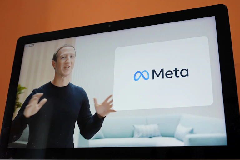 A man on a screen talks in front of a sign that says Meta.