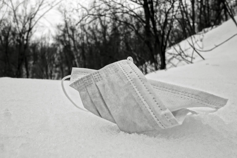 Masque chirurgical abandonné sur la neige.