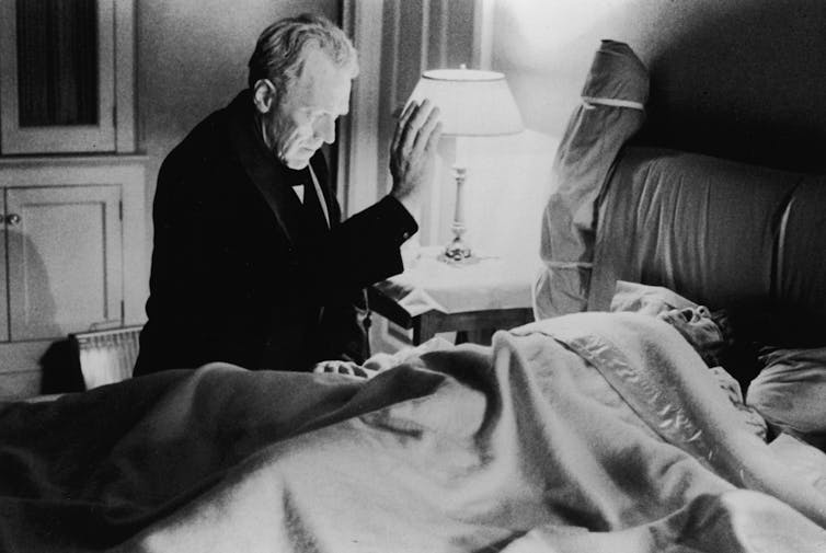 A priest blesses the young girl who is a in a possessed state, in the 1973 film, 'The Exorcist.'