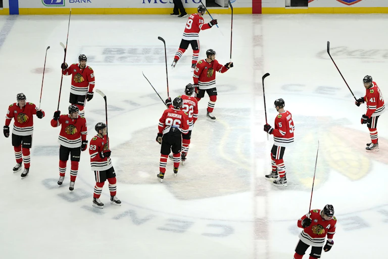 The Chicago Blackhawks skate around centre ice holding their sticks up in the air, celebrating a win