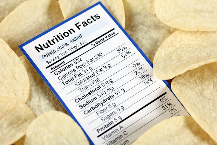 A nutrition label for potato chips lying on top of potato chips