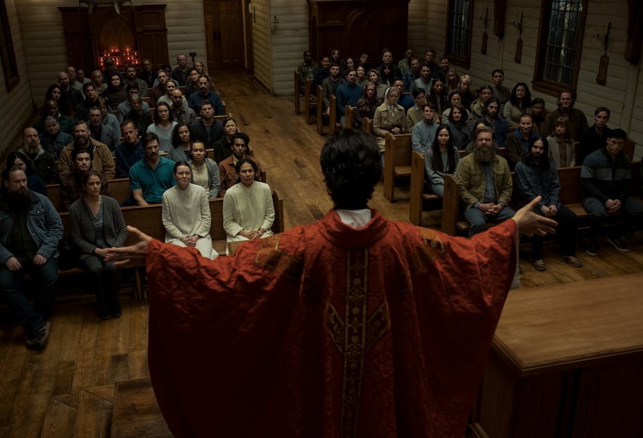 A priest blessing his congregation in a still from the Netflix series, "Midnight Mass."