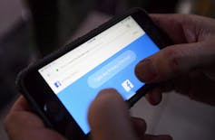 A cell phone user thumbs through the privacy settings on a Facebook account