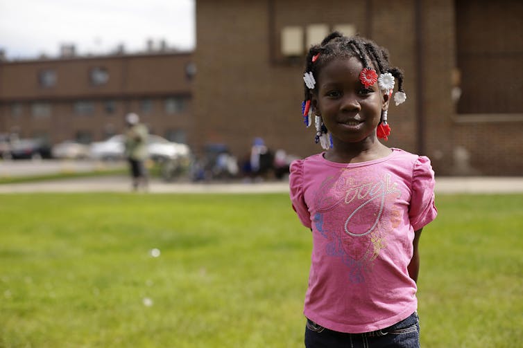 Young girl in front of a public housing complex.