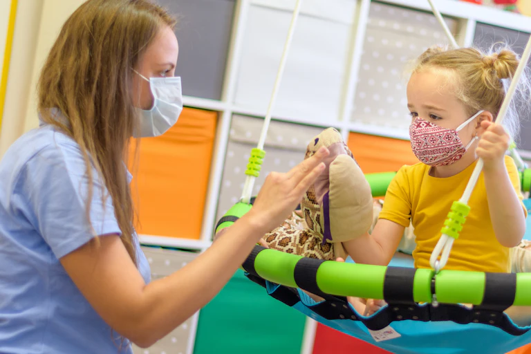 A girl in child occupational therapy session doing playful exercises with her therapist.