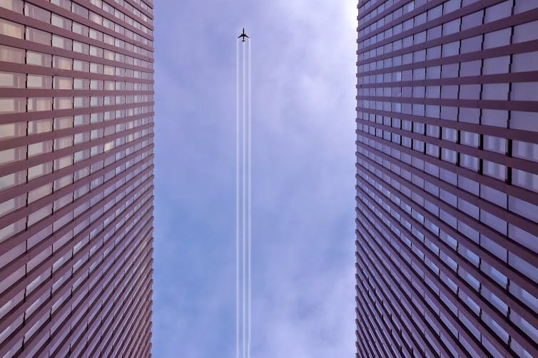 An aeroplane's trail viewed from between two tall buildings