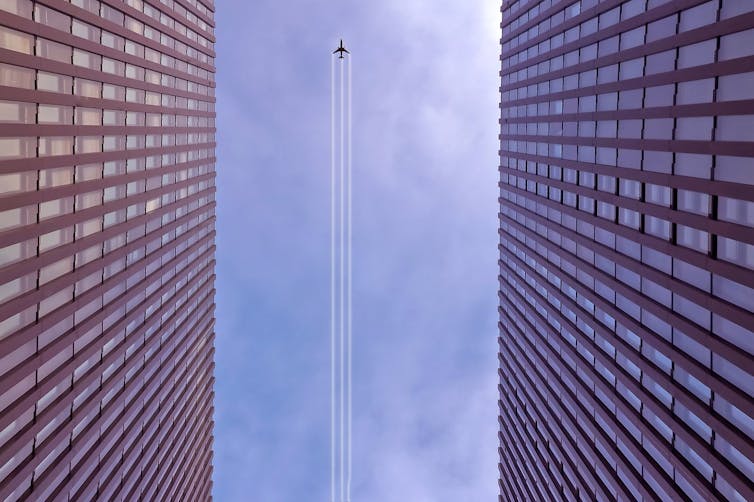 An aeroplane's trail viewed from between two tall buildings