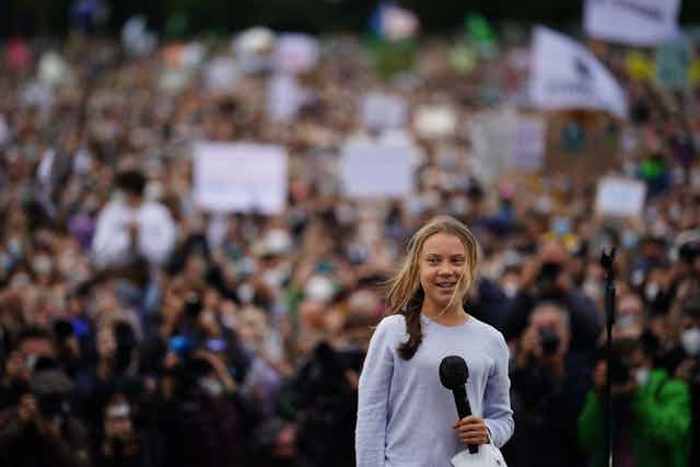Girl holds microphone, crowd in background