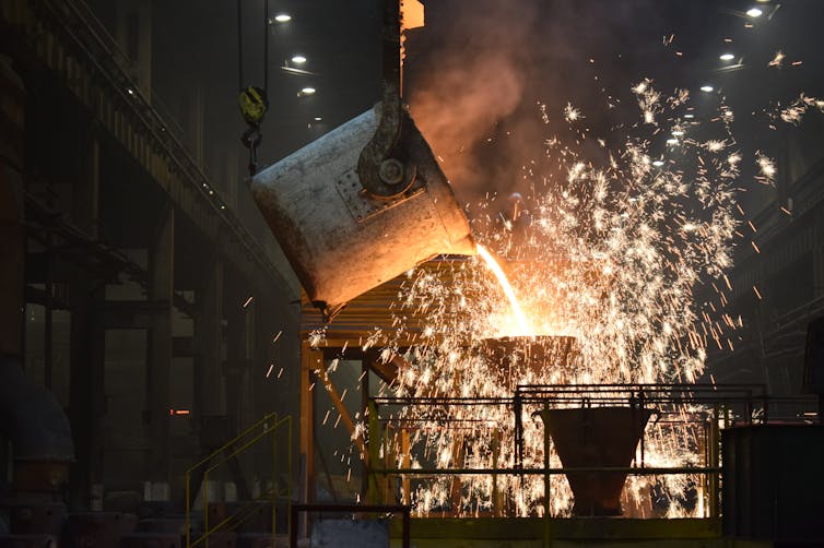 A vat of molten metal pouring onto a surface in a steelworks.