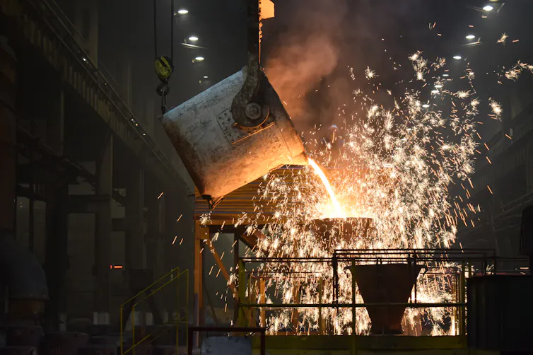 A vat of molten metal pouring onto a surface in a steelworks.