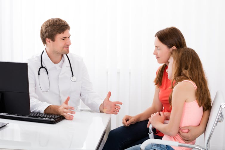 A teen girl and her mom speak with their male GP.