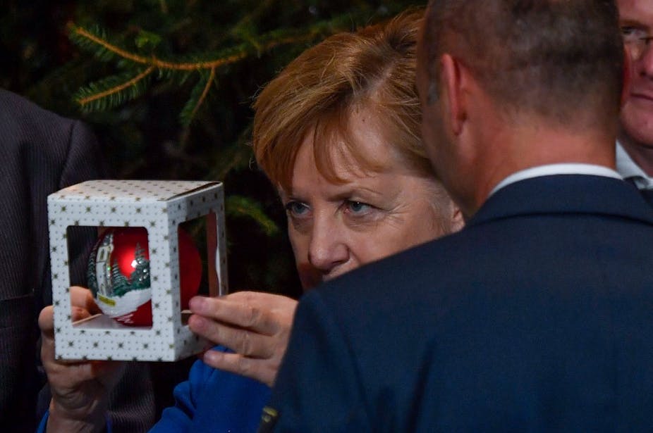 Angela Merkel inspecte une boule de Noël sous un sapin