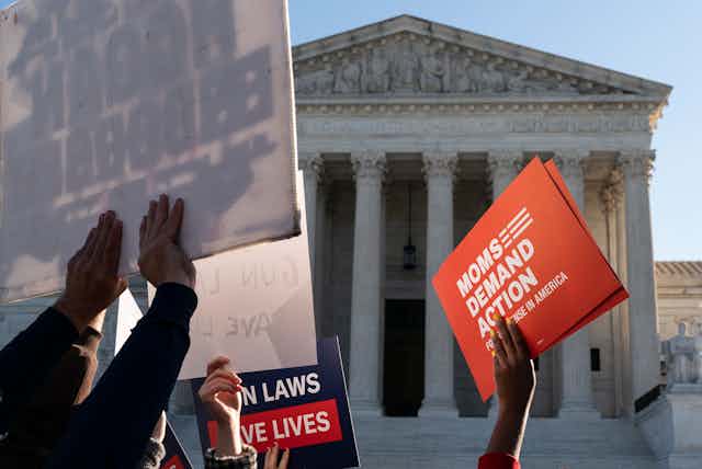 Pro-gun restrction placards are held aloft in front of the Supreme Court building.