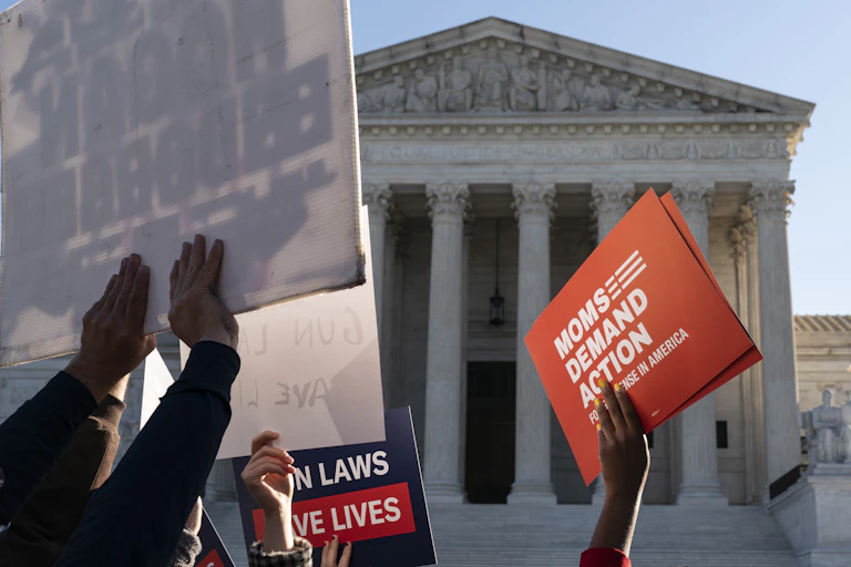 Pro-gun restrction placards are held aloft in front of the Supreme Court building.
