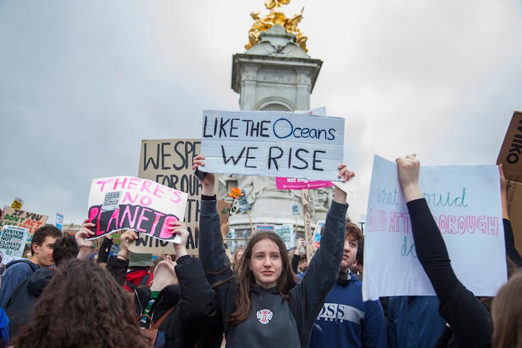 Girl holds up sign in front of monument