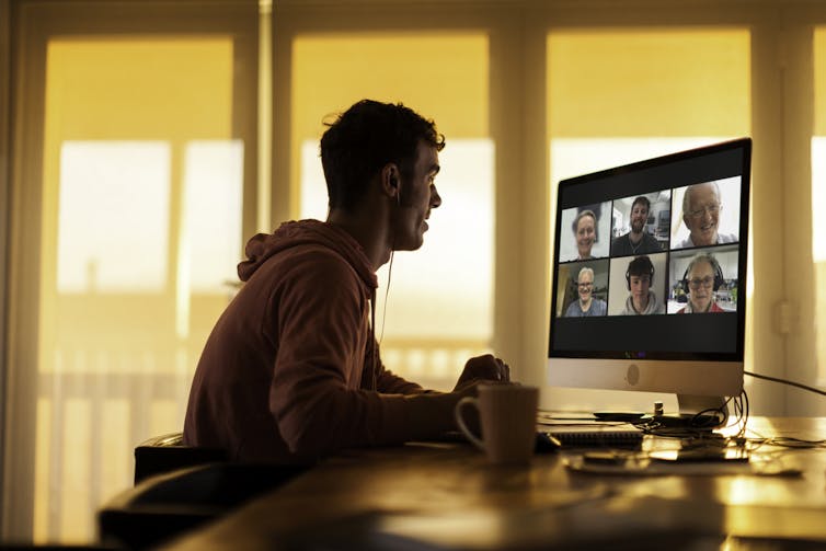 Young man in a hoodie Zooms with extended family members.