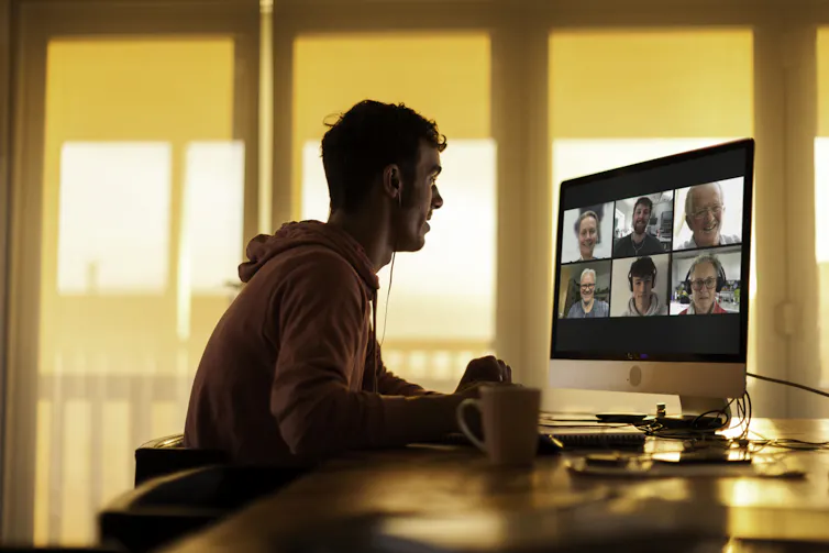 Young man in a hoodie Zooms with extended family members.
