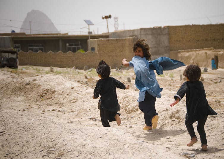 Children run next to building blocks.