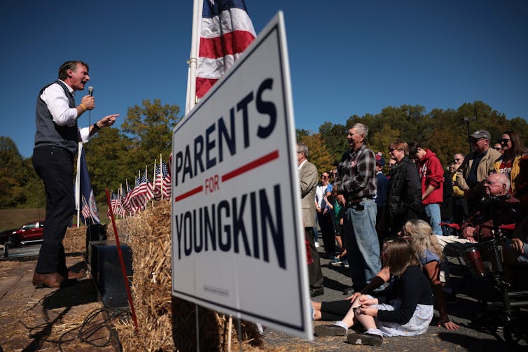 Glenn Youngkin at a campaign rally with a sign next to him that says