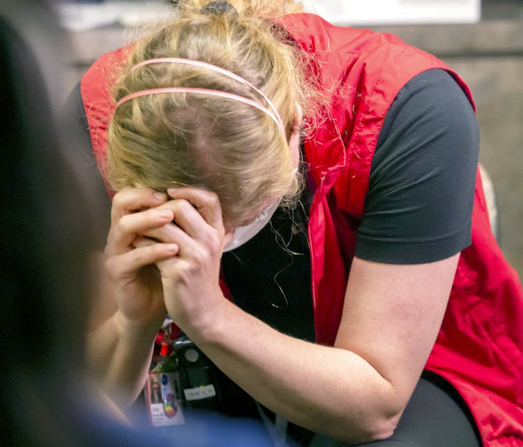 Nurse hunched over with head in hands.