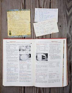 Handwritten recipe cards pictured above an open cookbook.