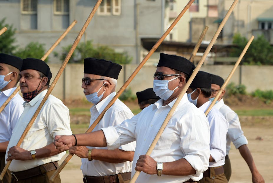 Five men, belonging to the Hindu nationalist group Rashtriya Swayamsevak Sangh, holding sticks and marching.